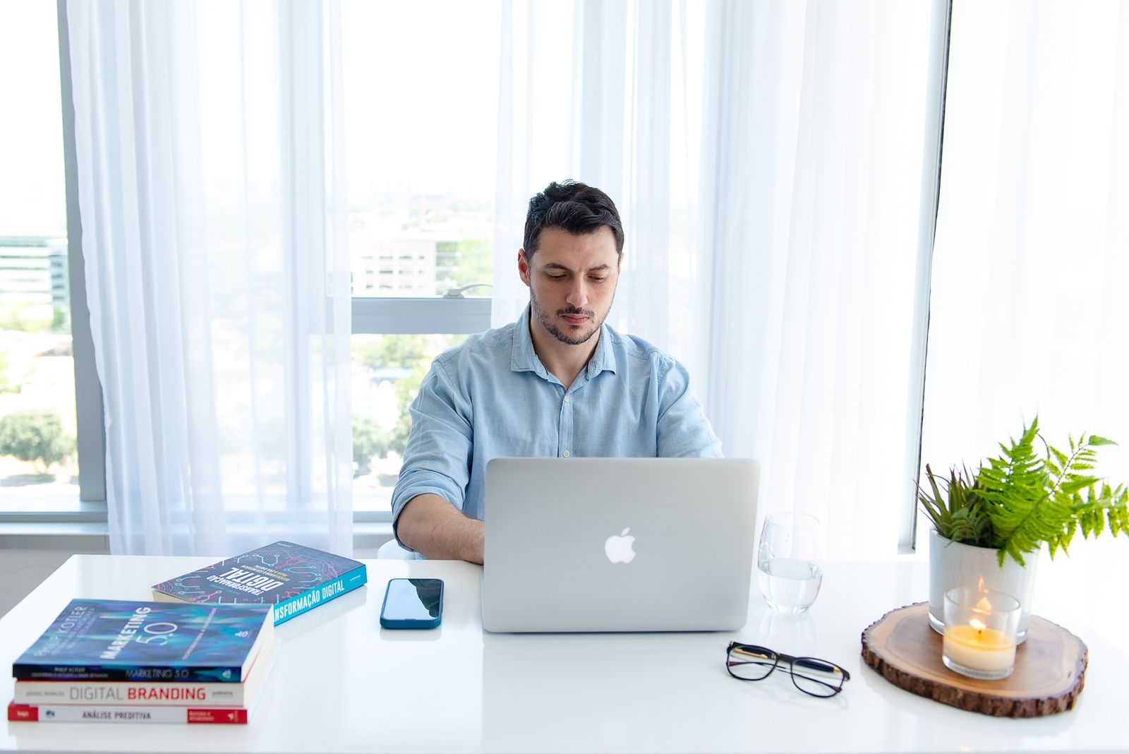 Aloisio Carlos à mesa de trabalho, com notebook e livros