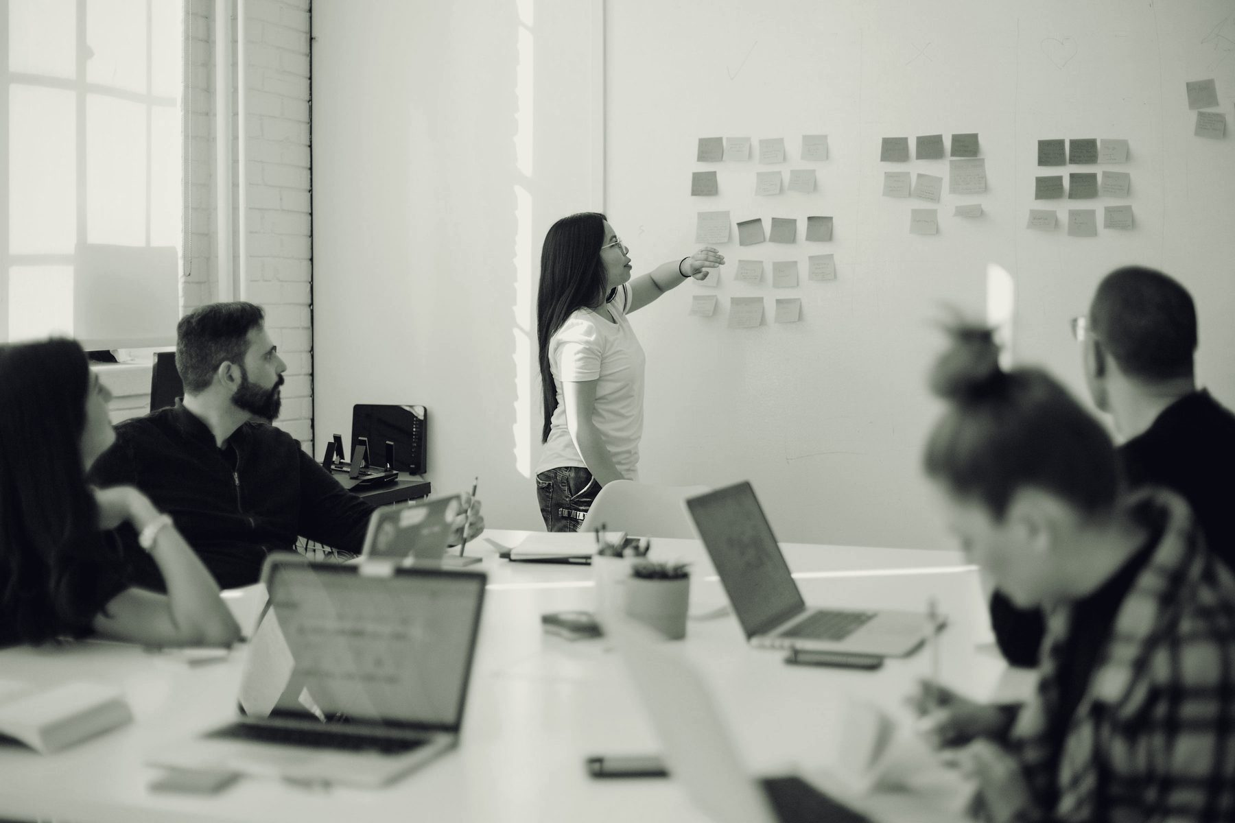 Equipe em sala de treinamento diante de um quadro com anotações